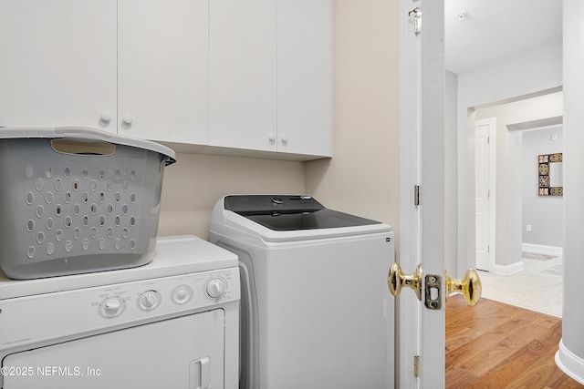 clothes washing area featuring light hardwood / wood-style flooring, washer and clothes dryer, and cabinets