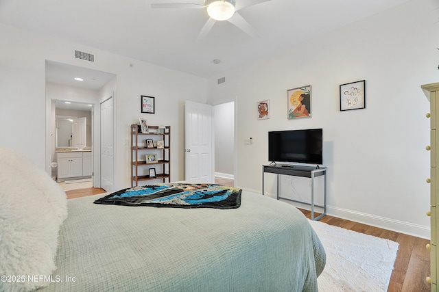 bedroom with light hardwood / wood-style floors, ceiling fan, and ensuite bath