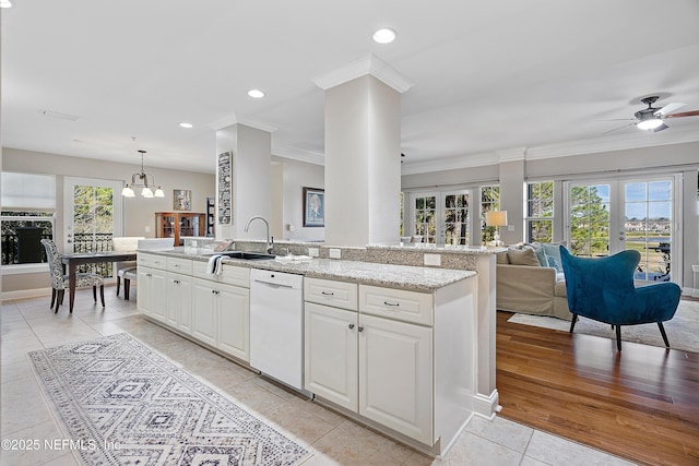 kitchen featuring sink, white cabinetry, hanging light fixtures, light tile patterned floors, and white dishwasher