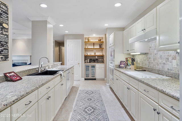 kitchen with sink, white cabinets, beverage cooler, light stone countertops, and white appliances