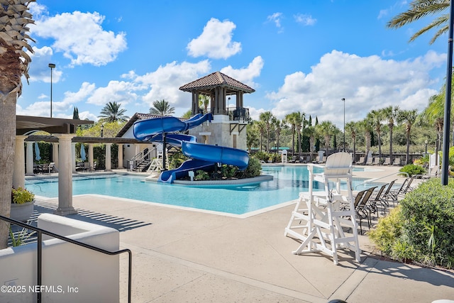 view of swimming pool with a water slide, a playground, and a patio