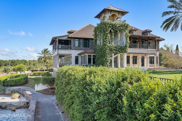 rear view of property with a balcony and a yard