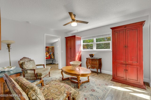 sitting room featuring ceiling fan, a textured ceiling, and light wood-type flooring