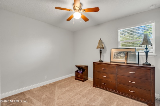 bedroom with ceiling fan, light carpet, and a textured ceiling