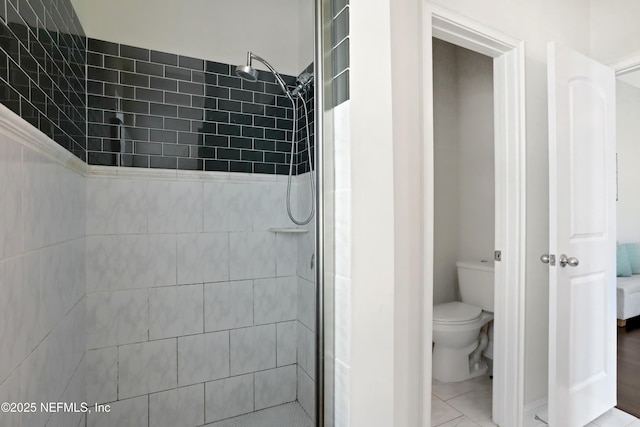 bathroom featuring a tile shower and toilet