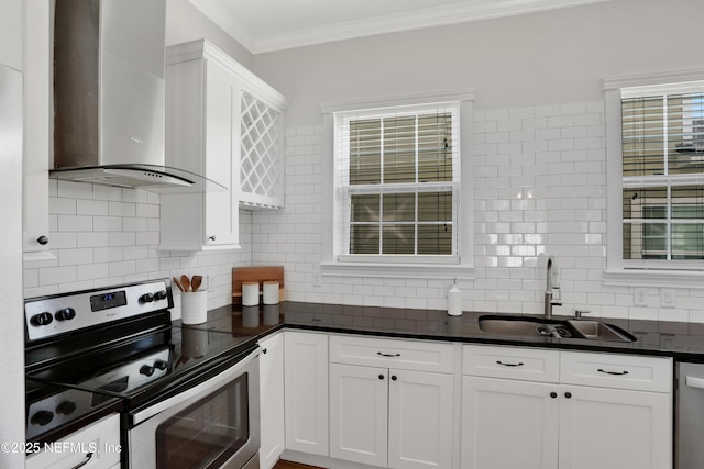 kitchen featuring sink, white cabinets, ornamental molding, stainless steel appliances, and wall chimney range hood