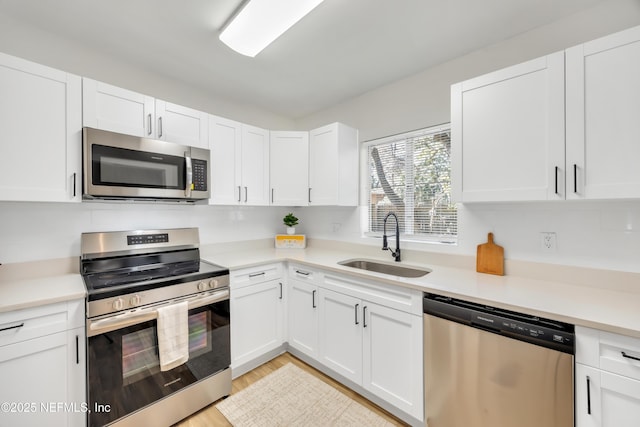 kitchen with sink, stainless steel appliances, light hardwood / wood-style floors, and white cabinets