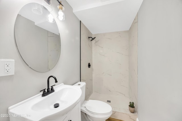 bathroom featuring vanity, a tile shower, and toilet