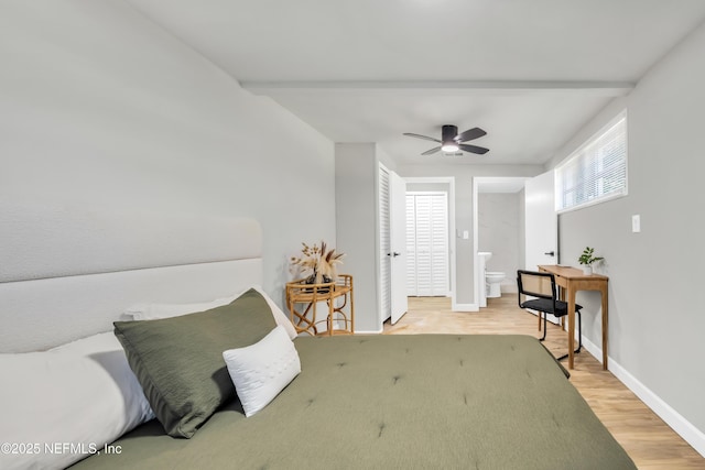 bedroom featuring ceiling fan, ensuite bath, beam ceiling, and light hardwood / wood-style flooring