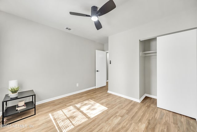 unfurnished bedroom featuring ceiling fan, a closet, and light hardwood / wood-style flooring