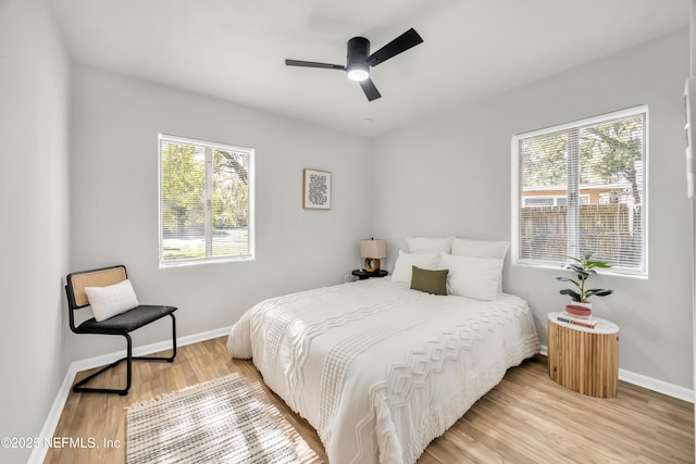 bedroom featuring multiple windows, hardwood / wood-style floors, and ceiling fan