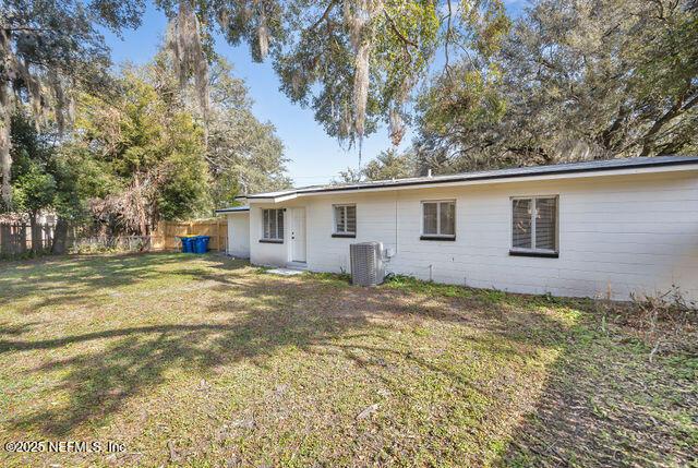 rear view of house with central AC and a lawn