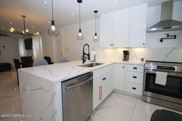 kitchen featuring wall chimney range hood, sink, appliances with stainless steel finishes, light stone countertops, and white cabinets