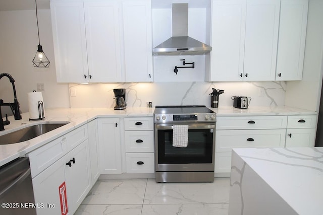 kitchen featuring wall chimney range hood, sink, hanging light fixtures, stainless steel appliances, and light stone counters