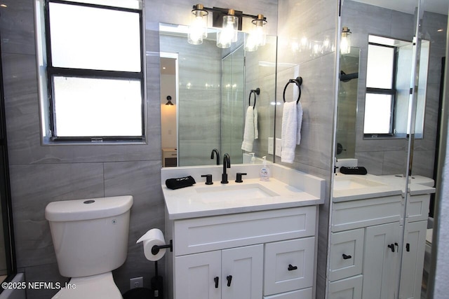 bathroom featuring vanity, a shower with shower door, tile walls, and toilet