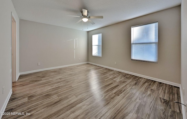 empty room with ceiling fan, a textured ceiling, and light wood-type flooring