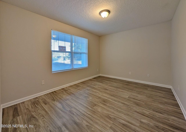 empty room with hardwood / wood-style floors and a textured ceiling