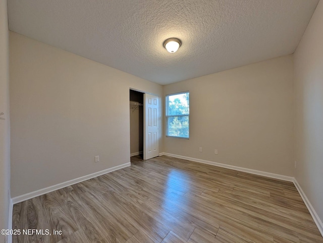 unfurnished bedroom with light hardwood / wood-style floors, a closet, and a textured ceiling