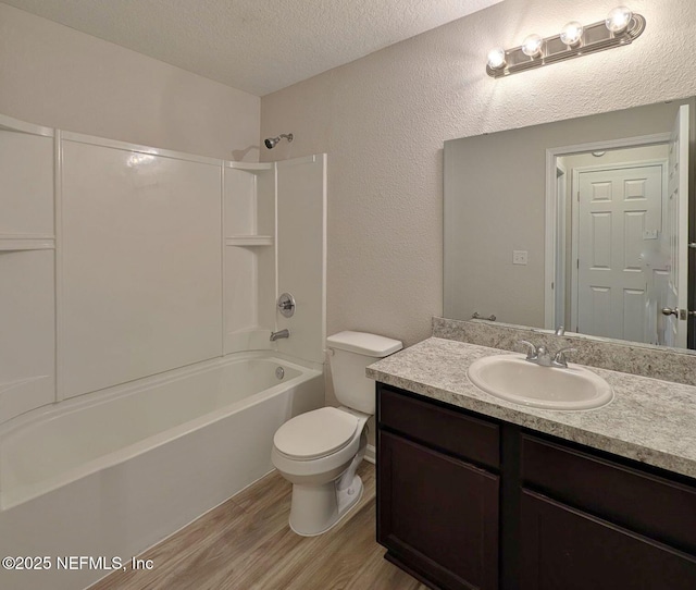 full bathroom with hardwood / wood-style floors, vanity, toilet, tub / shower combination, and a textured ceiling