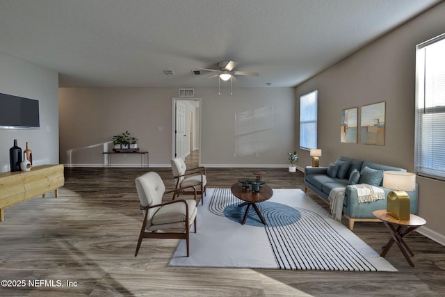 living room with ceiling fan, dark hardwood / wood-style floors, and a textured ceiling