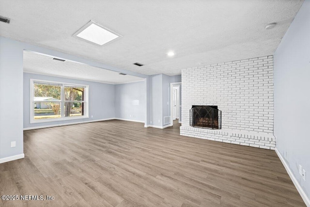 unfurnished living room with hardwood / wood-style floors, a brick fireplace, and a textured ceiling