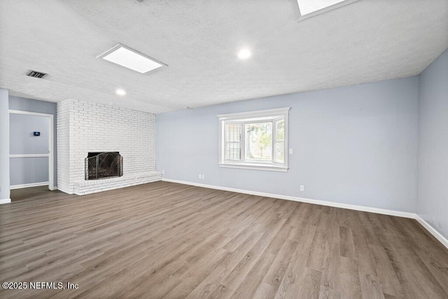 unfurnished living room with hardwood / wood-style floors, a textured ceiling, and a fireplace