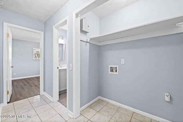 clothes washing area with light tile patterned flooring, hookup for a washing machine, and a textured ceiling