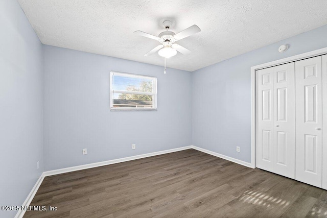 unfurnished bedroom featuring ceiling fan, dark hardwood / wood-style floors, a textured ceiling, and a closet