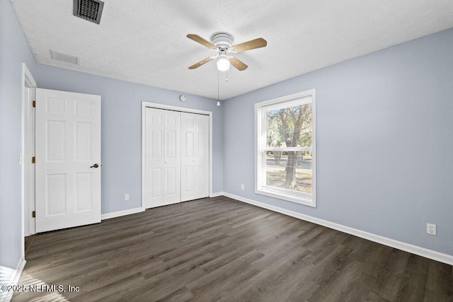 unfurnished bedroom with ceiling fan, dark hardwood / wood-style flooring, a closet, and a textured ceiling