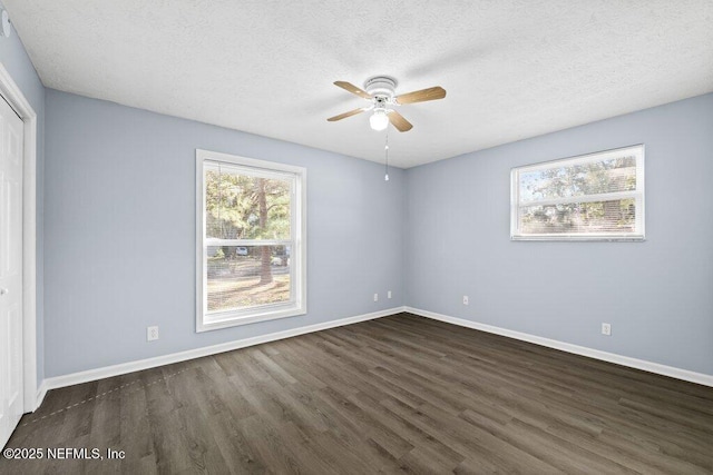 empty room featuring ceiling fan, dark wood-type flooring, and a textured ceiling