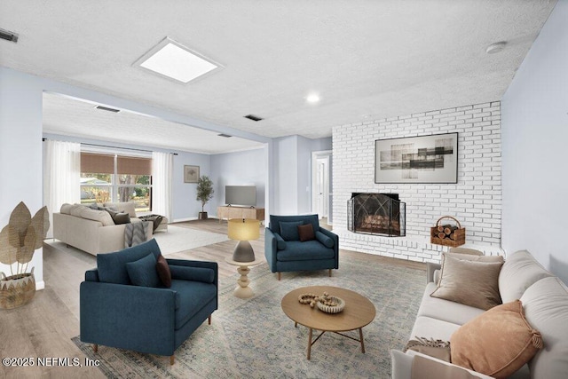 living room with a fireplace, light hardwood / wood-style floors, and a textured ceiling