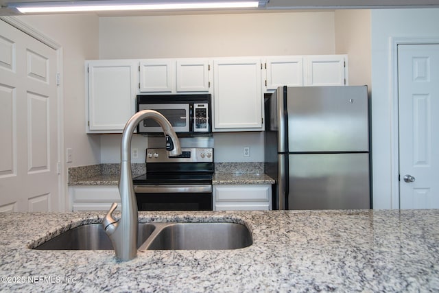 kitchen featuring light stone counters, sink, white cabinetry, and stainless steel appliances