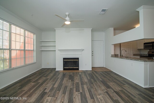 unfurnished living room with sink, ornamental molding, dark hardwood / wood-style floors, a tile fireplace, and ceiling fan