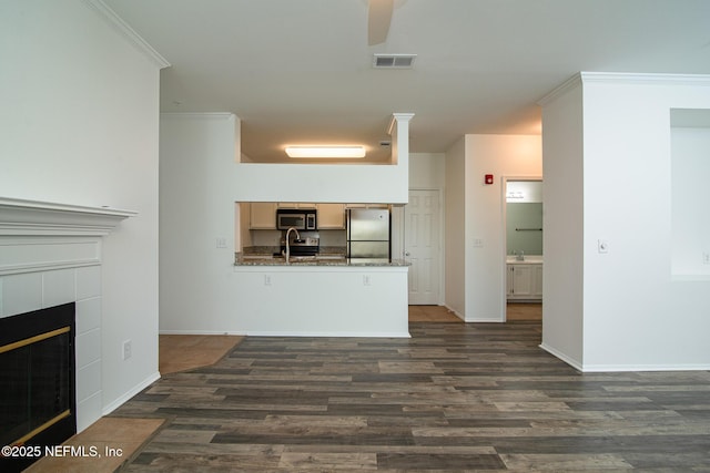 unfurnished living room with dark hardwood / wood-style floors, ornamental molding, sink, and a fireplace