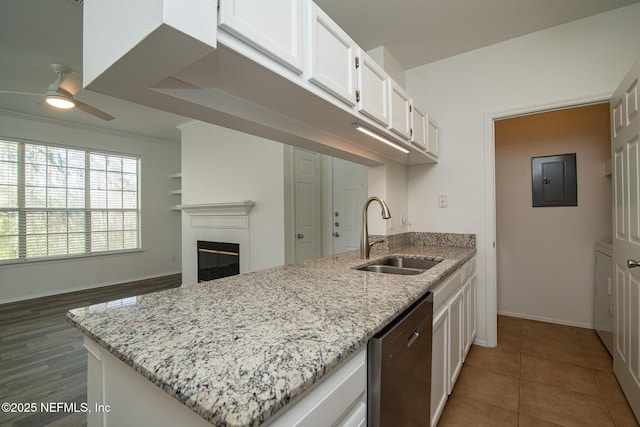 kitchen featuring sink, white cabinetry, light stone counters, dishwasher, and a tile fireplace