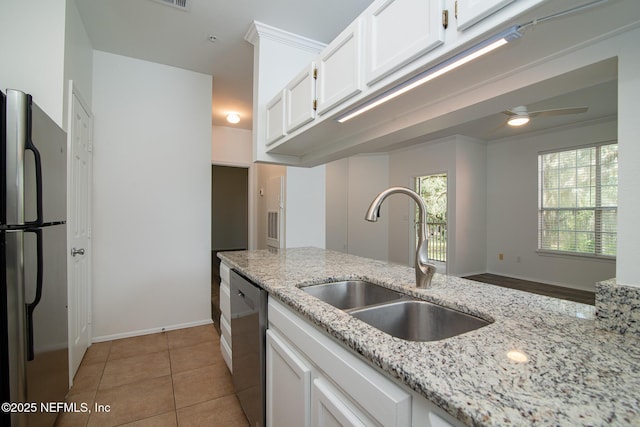 kitchen featuring sink, light stone counters, light tile patterned floors, appliances with stainless steel finishes, and white cabinets