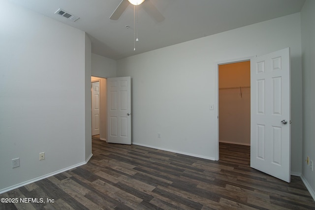 unfurnished bedroom with ceiling fan, a spacious closet, dark hardwood / wood-style floors, and a closet