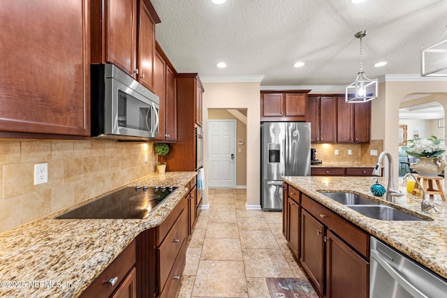 kitchen featuring sink, hanging light fixtures, stainless steel appliances, light stone counters, and ornamental molding