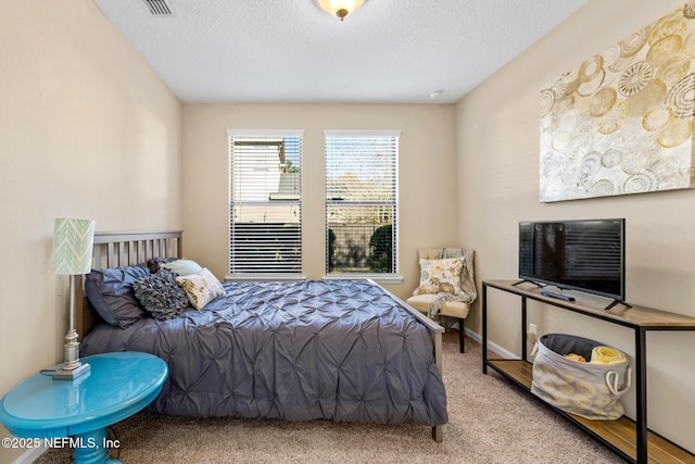 bedroom featuring light carpet and a textured ceiling