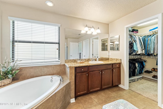 bathroom featuring vanity, a relaxing tiled tub, tile patterned floors, and a textured ceiling