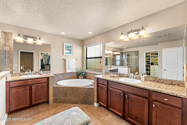 bathroom with vanity, independent shower and bath, tile patterned flooring, and a textured ceiling