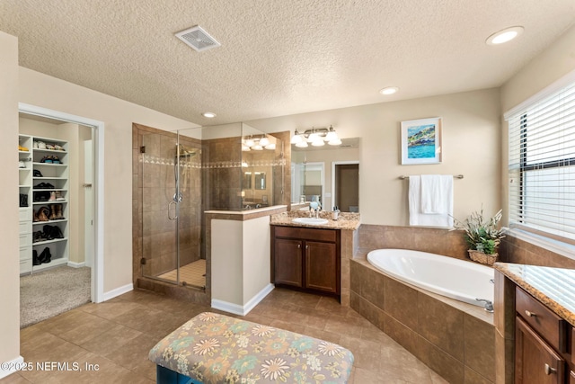 bathroom featuring independent shower and bath, vanity, tile patterned flooring, and a textured ceiling