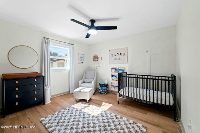 bedroom with ceiling fan, light hardwood / wood-style flooring, and a crib