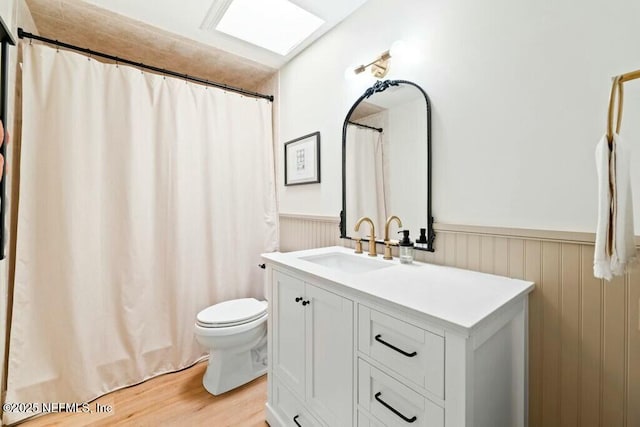 bathroom with hardwood / wood-style flooring, vanity, a skylight, and toilet