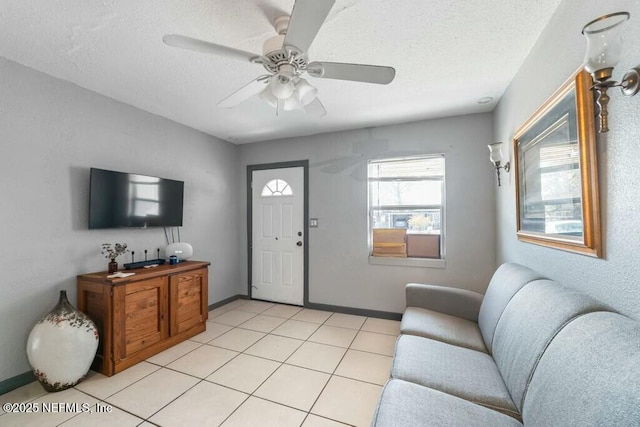 living room featuring ceiling fan, light tile patterned floors, and a textured ceiling