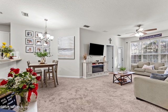 living room with light carpet, ceiling fan with notable chandelier, and a textured ceiling