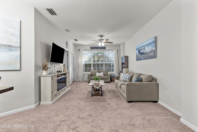 living room featuring light carpet, ceiling fan, and a textured ceiling