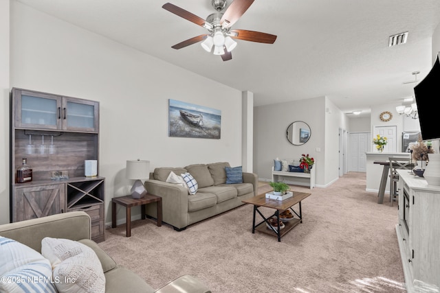 living room featuring ceiling fan with notable chandelier and light colored carpet