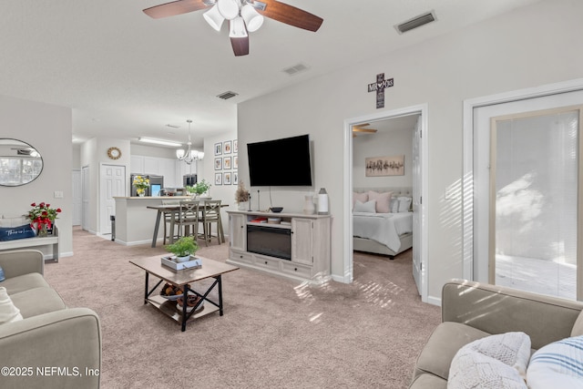 carpeted living room featuring ceiling fan with notable chandelier