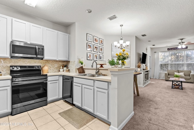 kitchen featuring electric range oven, white cabinetry, sink, hanging light fixtures, and kitchen peninsula